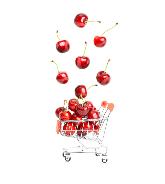 成熟的甜樱桃落入一个微型玩具购物车孤立在白色的背景。图片下载