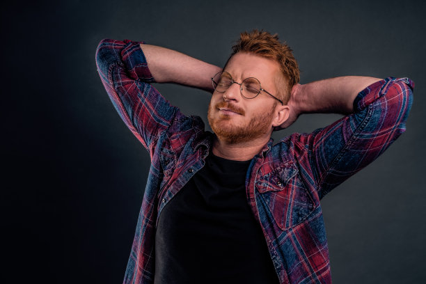 腰高的照片自信和放松的男性红发白人在眼镜和格子衬衫，手后面的头和自信的表情微笑，放松后的体育运动图片下载