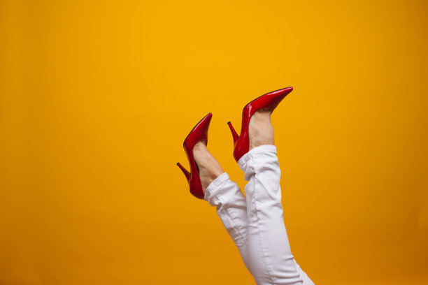 女性脚上穿着漂亮的红色细高跟鞋，黄色背景复制空间。图片下载