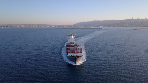 海洋中集装箱船鸟瞰图：满载货船在平静水面行驶图片下载