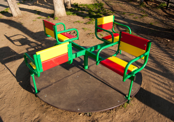 在一个阳光明媚的日子里，操场上的红黄绿旋转木马图片下载