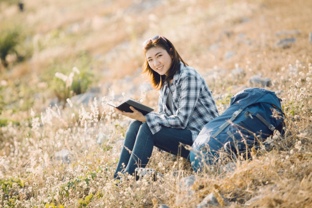 美丽的年轻亚洲女人写关于她的徒步旅行的日志，闪光图片下载