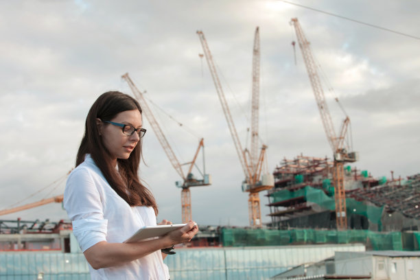 建筑师在施工现场进行监督。年轻的女工程师手里拿着平板电脑。图片下载