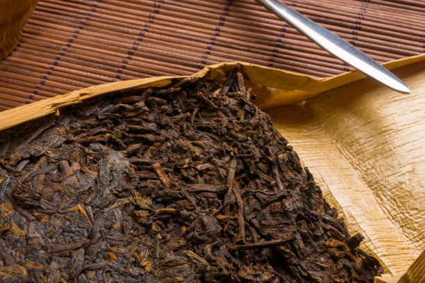 中国压普洱茶在竹叶包装和茶刀在竹席上，特写，宏观图片下载