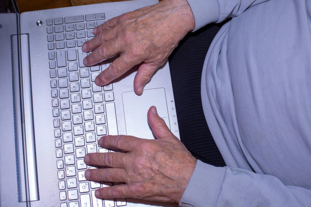 老人的手在电脑上打字。图片下载