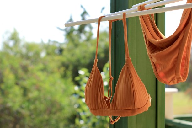 鲜橙色比基尼泳装挂在阳台的晾衣绳上风干。暑假的概念是度假、放松、度假。图片下载