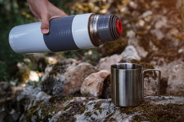 在野营杯子里，从热水瓶里倒茶。图片下载
