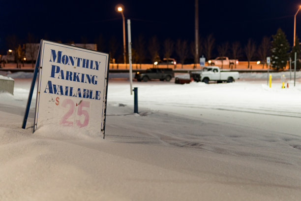 “每月25美元可停车”的牌子在冬天的晚上在停车场。摄于阿拉斯加安克雷奇市中心;W第三大道。图片下载