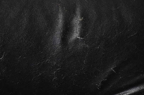 破旧的黑色真皮座椅内包海绵。室内装潢，破旧的旧皮沙发。黑色皮革纹理背景。图片下载