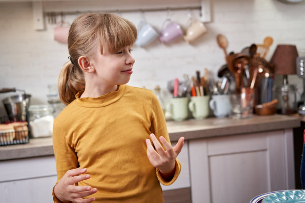 穿着黄色衬衫的可爱小女孩在家庭厨房吃华夫饼图片下载