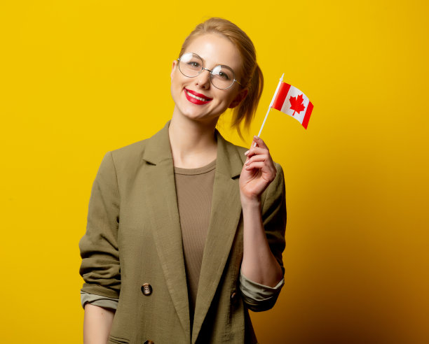 时髦的金发女子在夹克与加拿大国旗在黄色背景图片下载