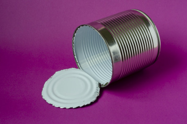 紫色的背景上是开着的空铁罐。图片下载