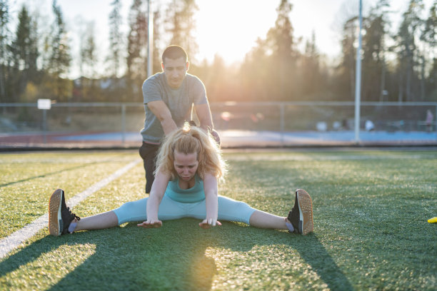 女运动员伸展时，教练帮助做正确的。图片下载