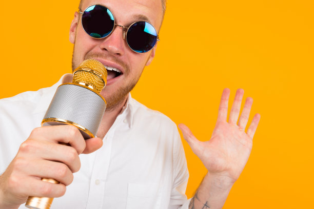 美丽的白人男子与眼镜唱卡拉ok与麦克风隔离在黄色背景图片下载
