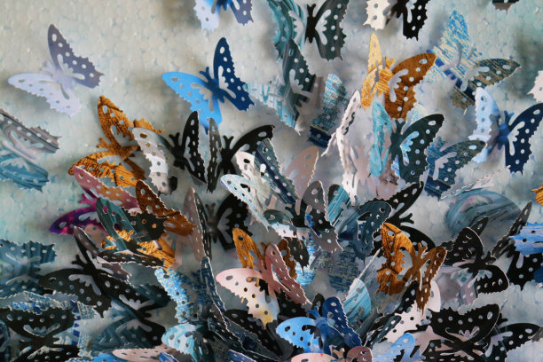近距离展示原工艺美术作品的彩色裁剪蝴蝶形状(帝王蝶-紫色，蓝色，橙色，粉红色和黑色的颜色)，彩色的工艺美术项目显示在墙上作为背景墙纸图片下载