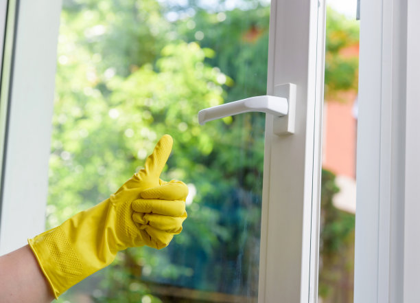 双手防护手套在干净的塑料乙烯窗背景上显示超级手势图片下载