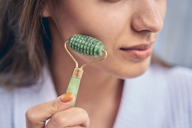 年轻女子完美的皮肤使用脸部按摩器图片下载