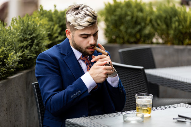 在咖啡馆里抽着雪茄喝着威士忌的帅气男子图片下载