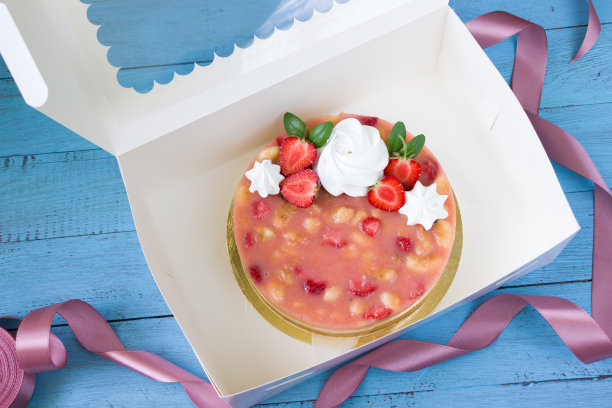 美味的草莓香蕉芝士蛋糕，白色的快递盒，蓝色的木板图片下载