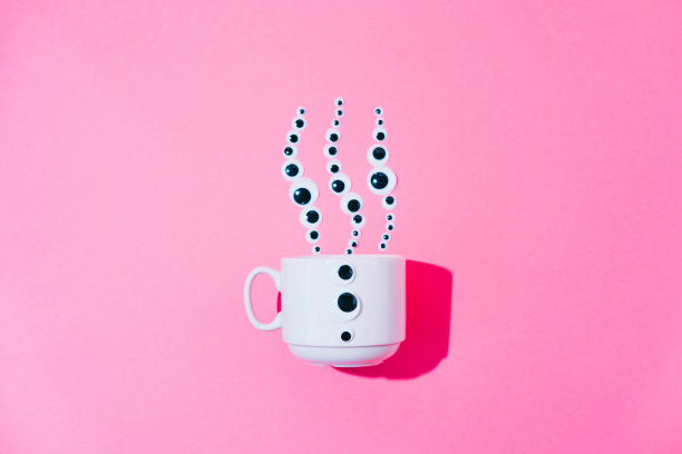 从一个白色的咖啡杯里喷出热气，在粉红色蜡笔超现实主义的背景上形成卡通玩具眼睛的形状。早餐极简主义。图片下载