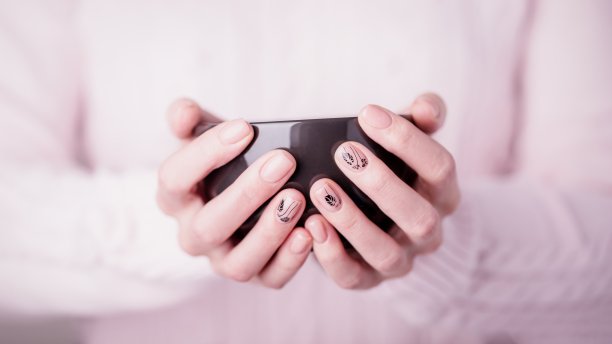 美丽的女性手握着黑色的杯子在粉红色的背景。指甲用粉红色指甲油图片下载