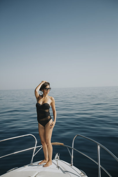 年轻女子穿着泳衣站在游艇前面图片下载