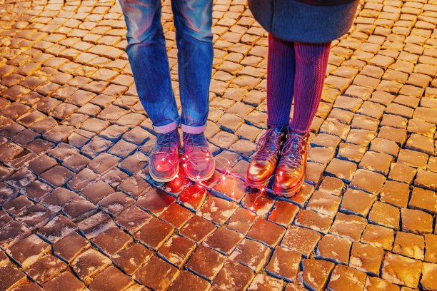 女性和男性的脚上戴着花环或圣诞彩灯在人行道上图片下载