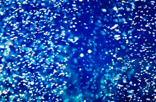 蓝色的散景背景，各种形状的雨滴纹理，被散景照亮。模糊滴在蓝色的黑暗背景。图片下载
