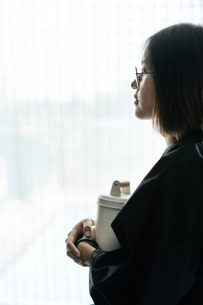 那个女人穿着黑色长袍，拥抱着tiffin，看着外面。图片下载