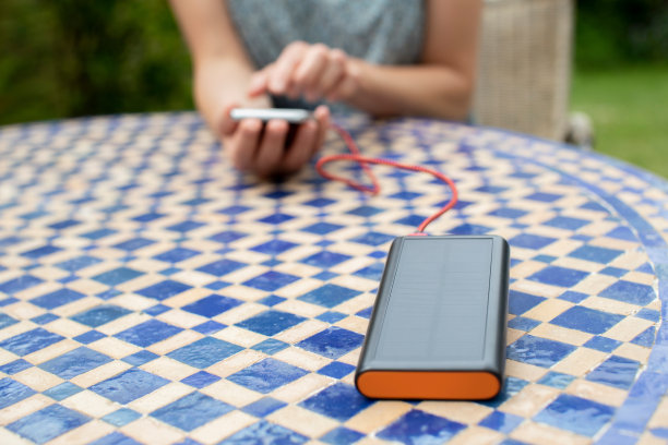一名妇女在家用便携式太阳能电池为手机充电图片下载