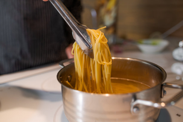 厨师用漏勺从锅里拿出热气腾腾的鸡蛋面图片下载