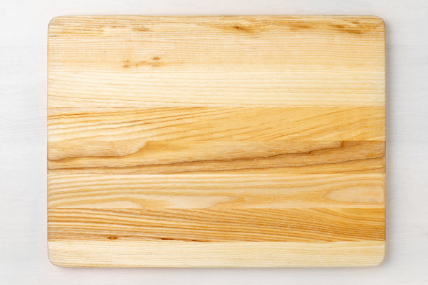 黄色的木砧板放在白色质朴的木桌上。平面拍摄。图片下载