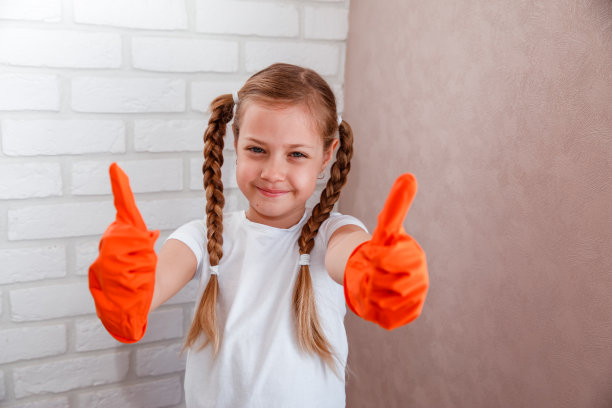 戴着橙色手套的小女孩正在打扫房间。图片下载