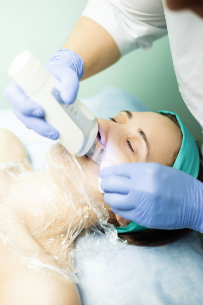 女性用超声波设备清洁面部皮肤的照片，健康和美丽的概念图片下载