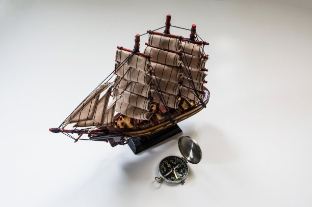 一个护卫舰模型和一个小袖珍罗盘在一个明亮的背景。图片下载