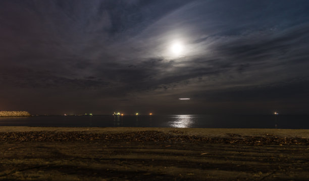 有沙滩的海景，平静的大海和月亮的轨迹。月光下的平面光迹图片下载