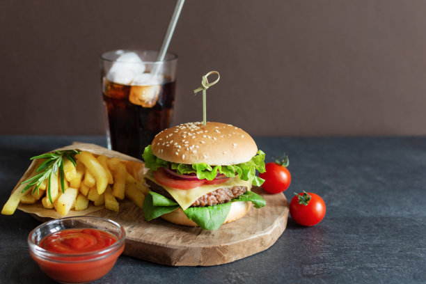 快餐汉堡菜单，炸薯条和可乐饮料在黑色的桌子背景。图片下载