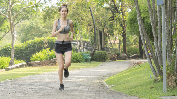亚洲漂亮苗条的女孩在时尚运动装是在公共花园晨跑。概念慢跑在他们的城镇和城市。图片下载