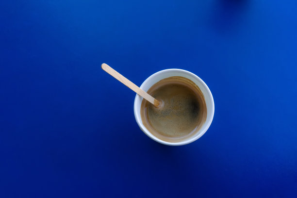 一杯咖啡在一次性餐具在蓝色背景表面的桌子。图片下载