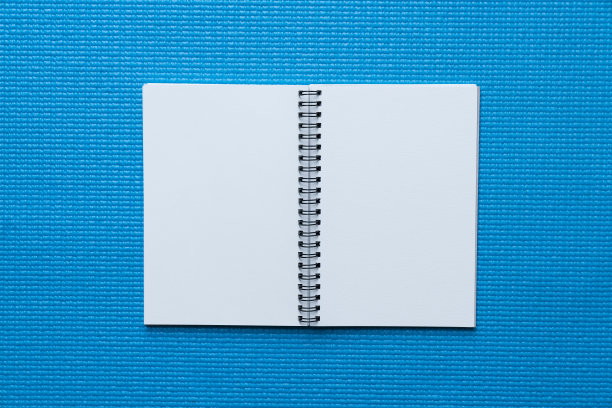 在桌子上的蓝色瑜伽垫上的笔记本特写，运动和健康的概念图片下载