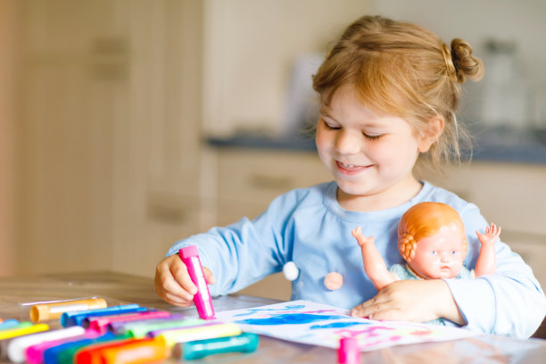 小女孩在冠状病毒隔离期间用毡笔画画。快乐的创意孩子与旧的古董娃娃，家庭教育和家庭日托与父母图片下载