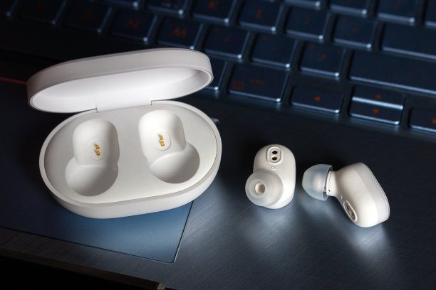 无线蓝牙耳机与充电器上的笔记本电脑背景特写素材图片