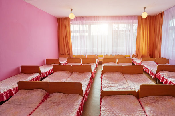 幼儿园幼儿园里有许多小床，上面铺着干净的床单，卧室内部空荡荡的，让孩子们可以舒服地睡上一个下午。儿童机构隔离的概念图片下载