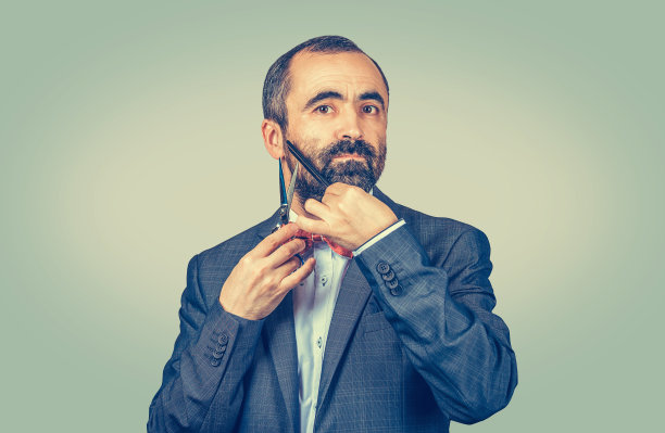 美发师，穿着优雅的夹克，带着红色的领结，摆着剪刀和梳子的姿势图片下载