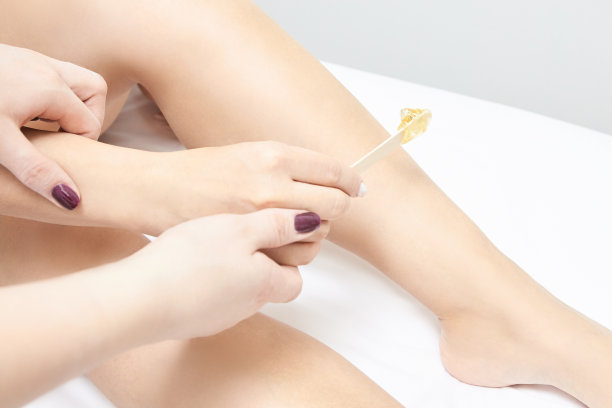 打蜡的女人的腿。糖脱毛。激光脱毛服务。美容院的蜡美容程序图片下载