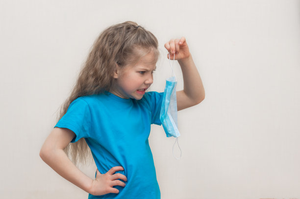 在家里的学龄前女孩的肖像。她手里拿着一个面具，很生气。闭关锁国则在摧毁隔离。在一个灯光背景上。本空间图片下载