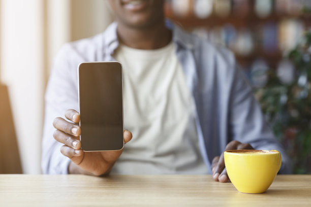 非裔美国人拿着黑屏手机在现代咖啡店，设计空间图片下载