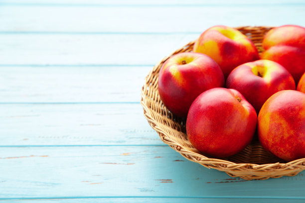 油桃篮子在蓝色的木制背景与拷贝空间图片下载