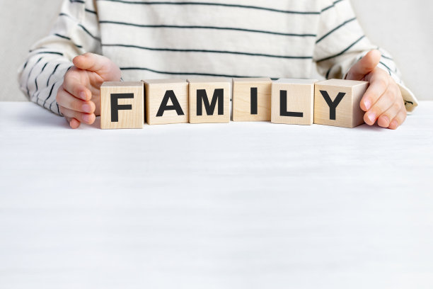 查尔德的手拿着带有字母的立方体，把单词family放在了桌子的表面上。父母和孩子之间的关爱、养育、信任和相互理解。空间背景,副本。图片下载