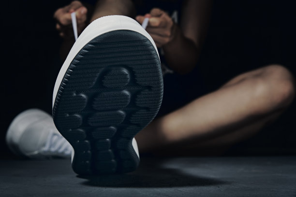 女人双手系鞋带的运动鞋在黑暗的背景。准备锻炼的健身运动员图片下载